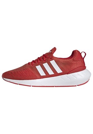 Raudoni sportiniai bateliai su tinklelio viršutine dalimi, baltais trimis juostelėmis, paminkštintu kraštu ir baltu, tekstūruotu tarpu. Lieknas, lengvas dizainas.