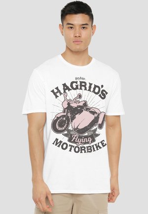 Young man wearing a white t-shirt with a vintage-style graphic of Hagrid's flying motorbike from Harry Potter.