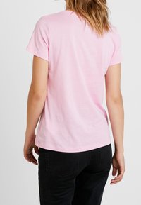 Ljusrosa bomulls t-shirt med korta ärmar, rund hals och en avslappnad passform. Baksidan visar en enkel, slät textur utan utsmyckningar.