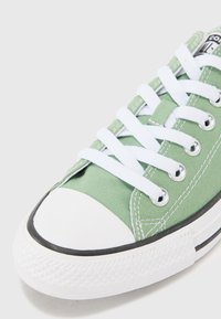 Grønne kanvas sneakers med hvite snøringer, gummitåhette og svart kant. Har metallhorn og teksturert såle for grep.