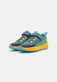 Baskets de sport grises et bleues avec des accents verts et jaunes. Caractéristiques d'un dessus en maille, d'une sangle Velcro et d'une semelle en caoutchouc texturée pour l'adhérence.