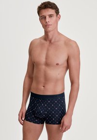 Navy blue boxer briefs with a patterned design in diamonds, featuring a soft waistband with the brand "CALIDA" displayed.