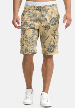 Shorts cargo beige avec un motif floral gris foncé, dotés de plusieurs poches et d'une taille plate avec le nom de la marque en bleu clair.