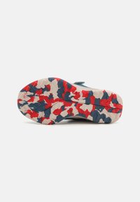 Shoe sole in white, red, and blue camouflage pattern with textured grip. Features a robust design and visible tread for traction.