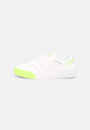 Baskets basses blanches avec des accents vert fluo sur l'orteil et le talon, détails perforés sur les côtés et texte "Court Tourino" sur le panneau latéral.