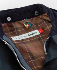 Wnętrze czarnej kurtki posiada brązową podszewkę w kratę z czerwonymi i żółtymi akcentami. Metka informuje "Paul Smith kocha Barbour" z metalowym zamkiem błyskawicznym.