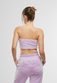 Lilla fløyels bandeau topp paret med matchende joggebukser med brodert "Von Dutch Originals" på ryggen. Glatt tekstur, tettsittende design.