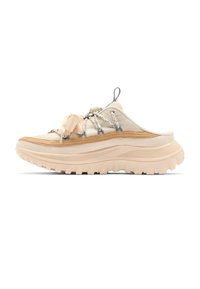 Beige slip-on sneaker with thick ridged sole, tan trim, patterned laces, and fabric pull tab at heel.