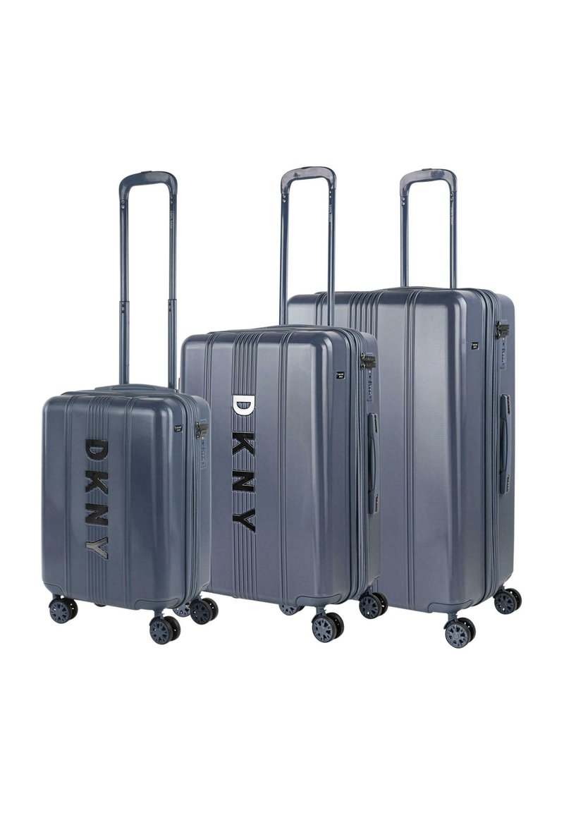 Tres maletas rígidas en gris con estrías verticales, que presentan la marca "DKNY" en negro, asas extensibles y ruedas giratorias.
