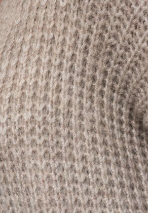 Texturerat stickat tyg i ljus beige, med en blandning av tjocka och tunna garn, vilket ger ett mjukt och mysigt utseende med synliga sömnads mönster.