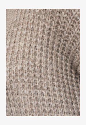 Tissu tricoté texturé en beige clair, présentant un mélange de fils épais et fins, créant une apparence douce et confortable avec des motifs de couture visibles.