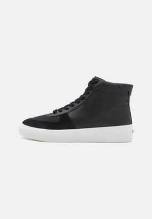 Black high-top sneakers made of smooth leather and suede with a white rubber sole, featuring a textured finish and black laces.