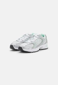 Zapatillas de running de malla plateada con detalles en verde menta, que cuentan con un diseño de cordones, lengüeta acolchada y suelas de goma negra.