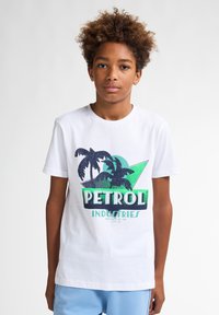 Camiseta de algodón blanca con un diseño gráfico de palmeras y el texto "PETROL INDUSTRIES" en verde y azul marino. Mangas cortas, cuello redondo.