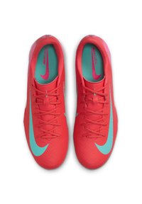 Piros szintetikus sportcipő sima felülettel, türkiz díszítéssel és fűzőkkel, valamint egy jellegzetes Nike logóval az oldalon.