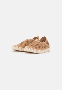 Scarpe slip-on di colore marrone chiaro, realizzate in materiale perforato con un design testurizzato. Presentano una suola in gomma bianca con bordo a zig-zag.