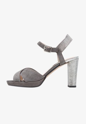 Sandale ouverte en suede gris avec une large sangle croisée et une sangle de cheville ajustable ; talon haut en métal argenté à texture craquelée.