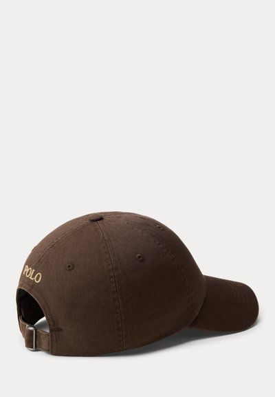 Șapcă de baseball maro cu curea reglabilă și cataramă metalică, cu inscripția "POLO" brodată cu fir auriu pe spate.