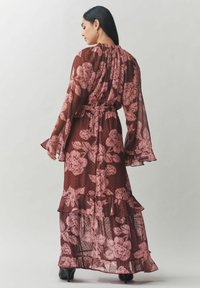 Ilga, plazdanti bordo spalvos su rožinėmis gėlių raštais ir taškeliais suknelė. Jungiami ruffles kraštai, ilgomis rankovėmis ir susiraukšlėtu iškirpimu.
