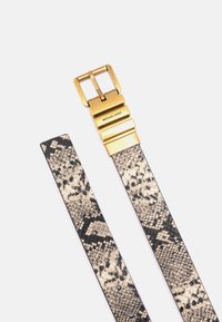 Leder-Gürtel mit Schlangenmuster in Beige und Schwarz, ausgestattet mit einer goudfarbigen Metallschnalle mit eingraviertem Branding. Strukturierte Oberfläche.