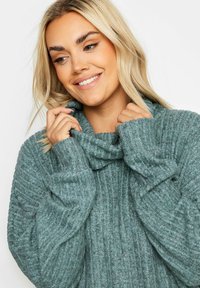 Knit-pusero, jossa on pehmeä teallinvärinen muotoilu, ribbireunus ja pitkät hihat, suunniteltu lämpöä ja mukavuutta varten.