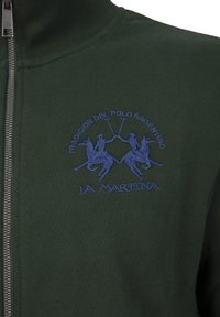 Dark green zip-up jacket made of soft fabric, featuring a blue embroidered design of two polo players and the logo "La Martina."