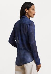 Navy blue sheer blouse with a collar, long sleeves, and button cuffs. Features a smooth texture and a slightly curved hem at the back.