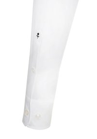 Manche de chemise blanche avec une broderie de rose noire près du poignet, ornée de trois boutons en perle et d'une texture lisse.