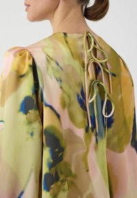 Vloeiende blouse met een veelkleurig bloemenpatroon in tinten geel, roze en blauw. Ontworpen met pofmouwen en lintaccenten aan de achterkant.