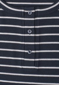 Gros plan sur un tissu côtelé bleu marine avec des rayures horizontales blanches et trois boutons ronds étiquetés "Street One" sur la patte d’une chemise.