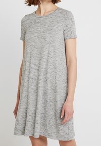 Robe grise à manches courtes en tissu doux et texturé avec une coupe décontractée et un col rond, présentant un motif chiné subtil.