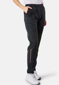Svarta, texturerade sweatpants med en avslappnad passform och resår i midjan. Har en rosa logotyp på sidan och sidofickor.
