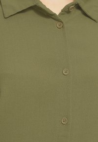 Olijfgroene overhemd met knopen, gemaakt van textiel met structuur, voorzien van een klassieke kraag en twee knopen aan de voorkant.