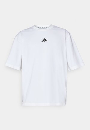 Hvit bomulls t-skjorte med en svart Adidas-logo på brystet, korte ermer, rund hals og sidesplitt ved kanten.
