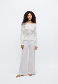 Haut à manches longues côtelé en crème clair avec motif floral bleu ; associé à un pantalon large gris clair ; tissu doux, coupe décontractée.