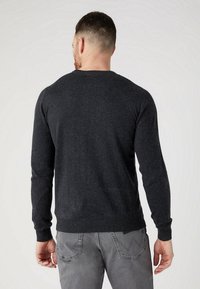Pull gris foncé à manches longues, avec des poignets et un ourlet côtelés, fabriqué en tricot, présentant un col rond classique et un design simple.