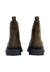 Botas de tobillo de ante marrón con un acabado texturizado, lengüetas en bucle y suelas de goma negra con profundas estrías para ofrecer tracción.