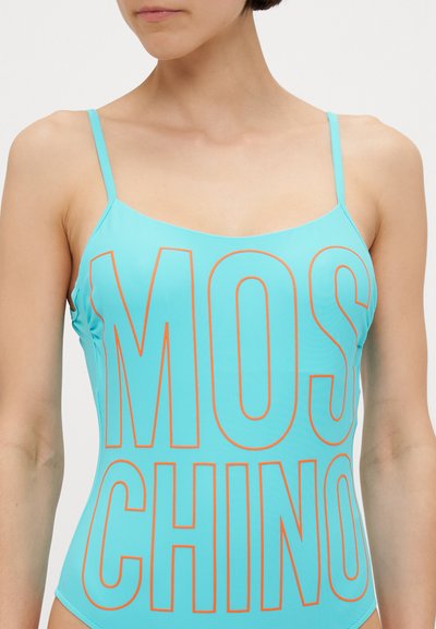 Türkise ühes tükis ujumistrikoo õhukeste rihmadega, millel on silmatorkav oranž "MOSCHINO" tekst ees; sile ja läikiv tekstuur.