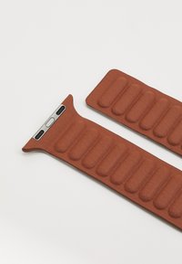 Brown leather watch band with cushioned segments and a silver hardware clasp. Features a smooth texture and a contoured shape for comfort.
