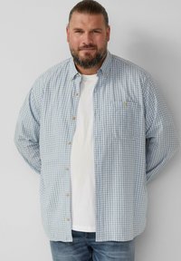 Lichtblauw geruit overhemd met knopen van katoen, voorzien van een borstzak, gecombineerd met een wit T-shirt en blauwe jeans. Heeft beige knopen.