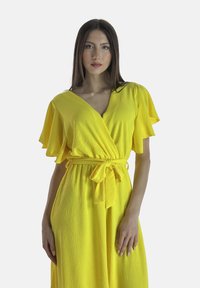 Gelbes Wickelkleid mit schwingenden Ärmeln, Taillengürtel und strukturiertem Stoff. Verfügt über einen tiefen V-Ausschnitt und einen knöchellangen Saum.
