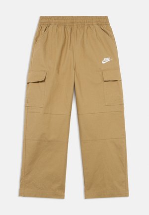Pantalon cargo beige Nike avec taille élastique, deux poches latérales à rabats, et un logo Nike blanc sur la cuisse droite.