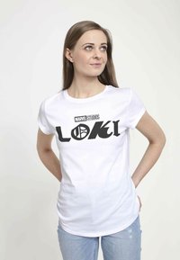 Camiseta de algodón blanca con un gran logo negro de "LOKI" y el texto "MARVEL STUDIOS". El diseño incluye gráficos en negrita y una silueta ajustada.