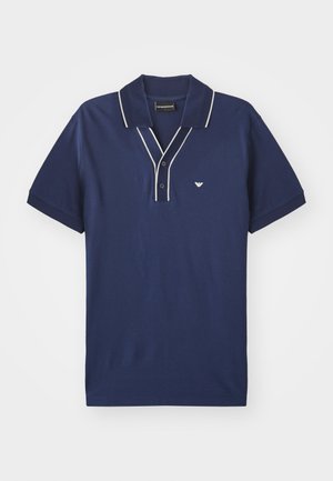 Polo shirt bleu marine en coton, avec un contraste blanc sur le col et la patte de boutonnage, et un petit logo sur la poitrine gauche.