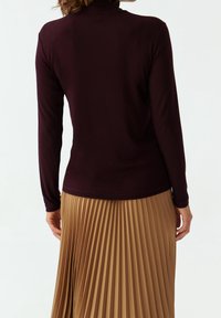 Burgundin pitkähihaine turtleneck-paita, joka on yhdistetty laskostettuun vaaleanruskeaan hameeseen. Sileä kangas, tiukka malli ja hienovarainen joustavuus.