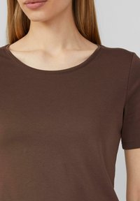 T-shirt marron à manches courtes avec un col rond, fabriqué en coton côtelé, présentant une texture lisse et un léger extensibilité.
