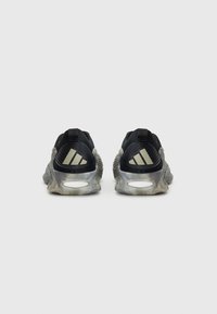 Une paire de sneakers Adidas noires et grises vues par l'arrière avec un logo blanc sur les talons et une semelle texturée sur un fond uni.