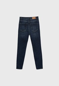 Vaqueros de mezclilla azul oscuro con un diseño ajustado, que cuentan con dos bolsillos traseros y un parche de cuero rectangular en la cintura.