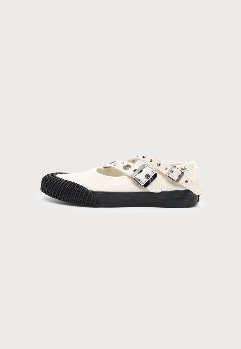 Chaussure plate en toile blanche avec embout et semelle en caoutchouc noir, avec deux brides réglables à boucle sur le dessus.
