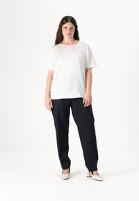 Top bianco a maniche corte, vestibilità rilassata. Abbinato a pantaloni blu navy a righe, design affusolato, e scarpe beige con tacco alto. Texture piatta in tutto.